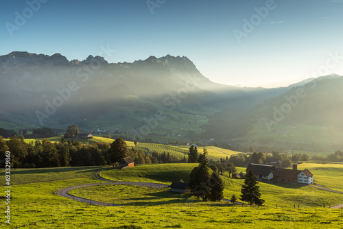 Rural landscape in the Appenzell region with farm houses and meadows in the last light of the evening sun, view to the Alpstein mountains with Saentis, Canton of Appenzell Innerrhoden, Switzerland photo
