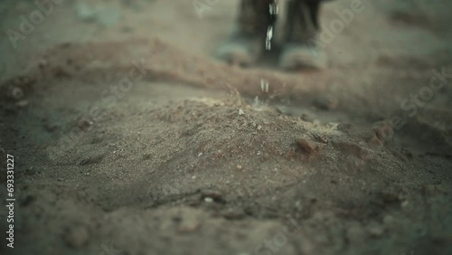 Person watering an arid desert terrain in slow motion. Close up. Environmental crisis photo