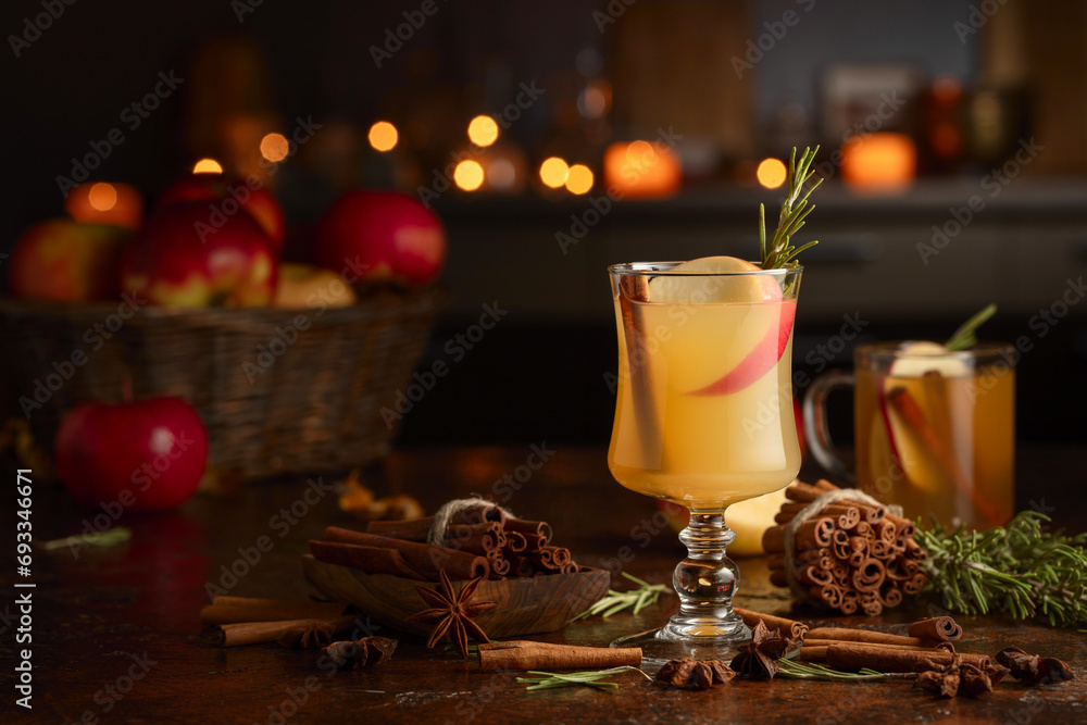 Mulled cider with apples, cinnamon, rosemary, and anise on a background of burning candles.
