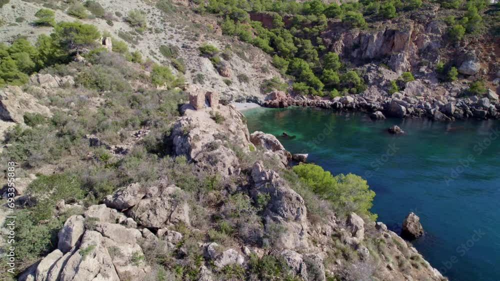 Seaside cliffs and medieval towers. Revealing aerial view of the beach with turquoise waters. Mediterranean Sea. Spain.