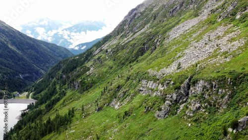 Steep mountain with a few cliffs next to an artificial lake in the Alps in Kaernten, Austria photo