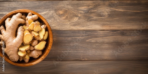 Ginger in bowl on wooden table at home, seen from above, empty area photo