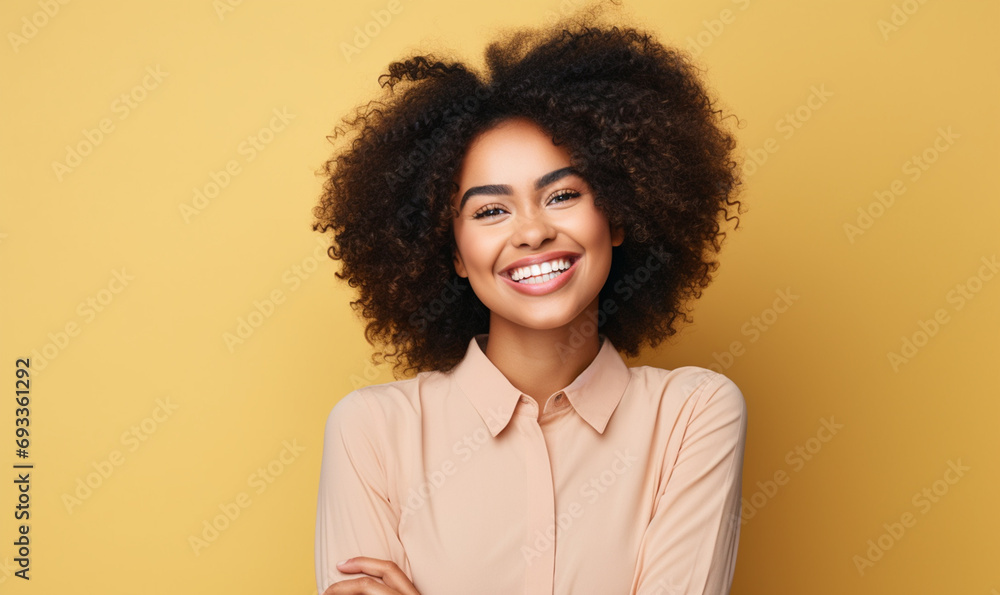 Fototapeta premium Portrait of beautiful young Beautiful African American girl with an afro hairstyle laughing. Isolated on yellow background