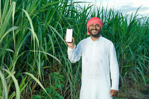 Indian farmer using smart phone at green farm field