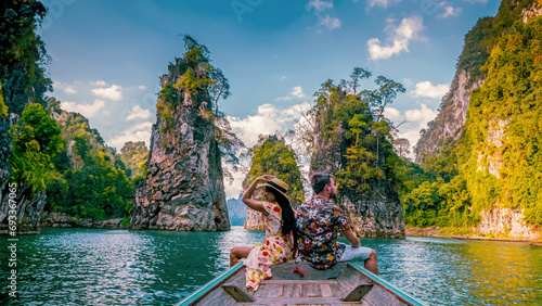 a couple traveling by longtail boat exploring epic limestone cliffs in a huge lake in Khao Sok National Park, Chiew Lan Lake, Thailand Surat Thani, men and woman in front of longtail boat photo