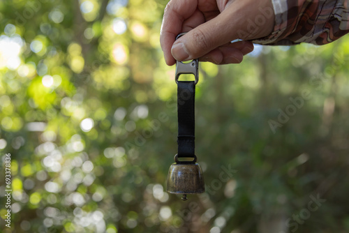 A bear bell with hand at the green forest in Autumn