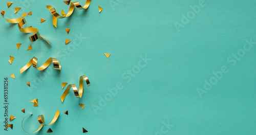 close up on group of gold color of rolling ribbon and confetti on teal background with copy space for christmas festival happy new year ,carnival , birthday and anniversary, concept design