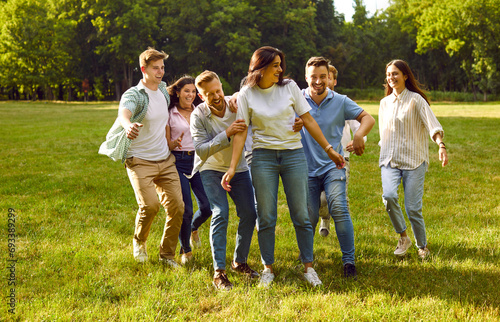 Group of young people hugging in the park. Happy, cheerful, joyful friends relaxing, having fun and hugging in a sunny, fresh, green park on a nice summer weekend