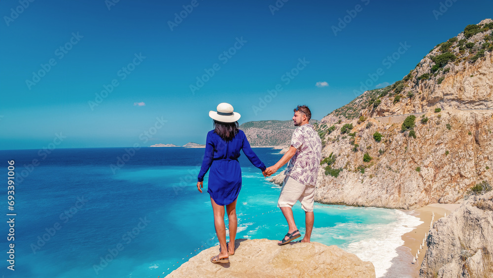 Obraz premium couple on vacation Turkey Kaputas Beach Kas Turkey, white orange beach from cliffs by the ocean of Kas Turkey rivera during summer, men and woman standing on cliff looking ocean during summer vacation
