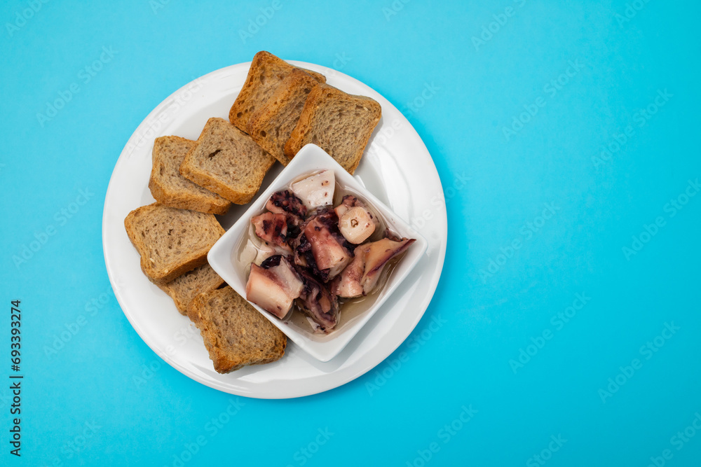 octopus salad with oil in small bowl and toasts