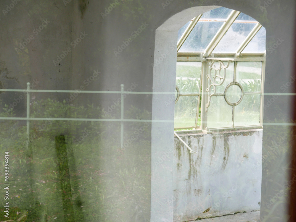 Interior of an old abandoned greenhouse with reflections on the glass of the nature around Interior of an old abandoned greenhouse with reflections on the glass of the nature around