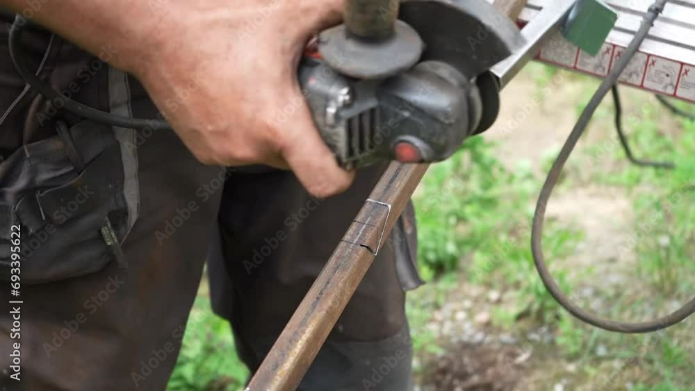Worker cutting metal tube using an Angle Grinder. Bright sparks and flashes Worker cutting metal tube using an Angle Grinder. Bright sparks and flashes