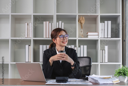 Portrait smiling Asian business woman uses laptop to work on financial transactions. Planning work on the desk in the office