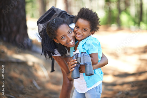 Portrait, binocular or black family hiking in forest to relax, hug or bond on holiday vacation together in nature. Child, happy or mom in woods or park to travel on fun outdoor adventure with smile photo