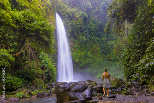 A young woman in a swimming suit at Nungnung waterfall in lush tropical forest  Bali  Indonesia