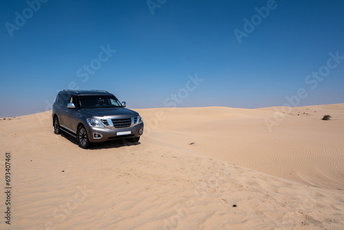 SUV four wheel drive vehicle car Al Qudra empty quarter seamless desert sahara in Dubai UAE middle east with wind paths and sand hills gray cloudy sky © SinanKocak