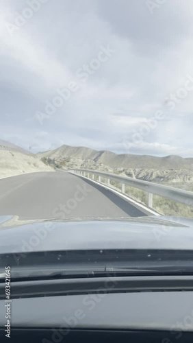 First person view, FPV, from dashcam of car driving on narrow back road in Tabernas desert, Almeria, Andalusia, Spain, Europe. Road trip vertical video in POV in arid, dry climate photo