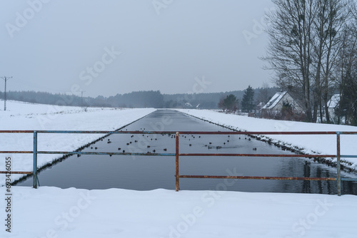 WINTER ATTACK - A snow covered bridge and fields on banks of the river
 photo