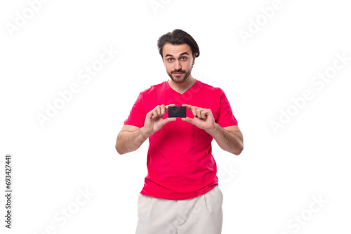 young brunette advertiser man dressed in a red t-shirt shows a plastic credit card