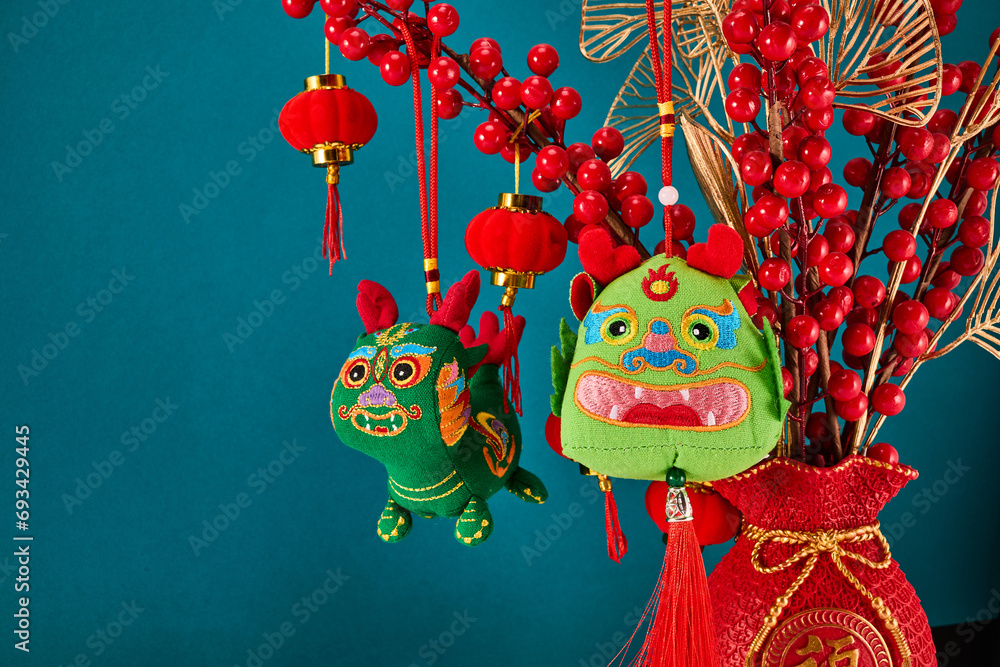 A New Year's toy in the shape of a green dragon hangs on a branch tree. Festive background. Chinese horoscope