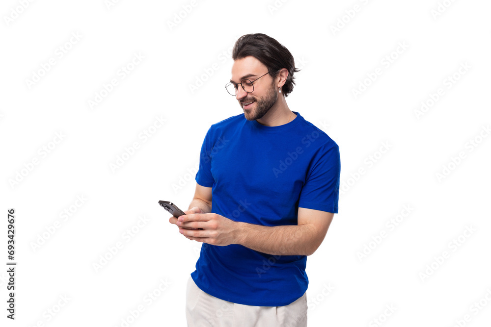 young handsome brunette man with a beard in a blue t-shirt chatting in a smartphone young handsome brunette man with a beard in a blue t-shirt chatting in a smartphone