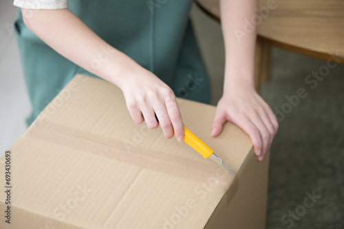 Opening a cardboard box with a cutter. © kapinon