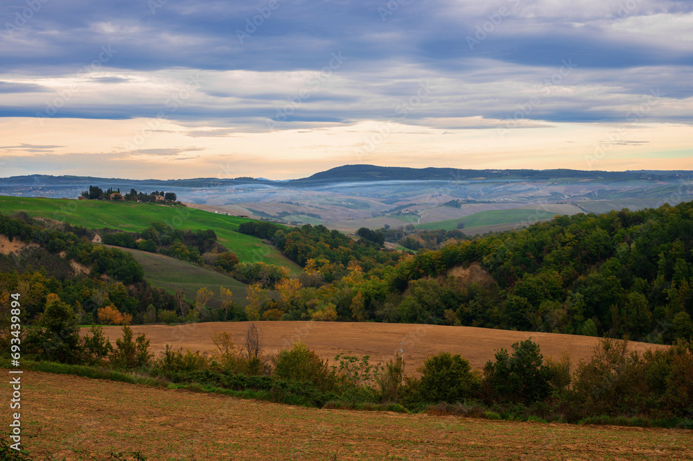 The picturesque authentic Italian landscape with villa, cypresses and plowed field in Tuscany, Italy.