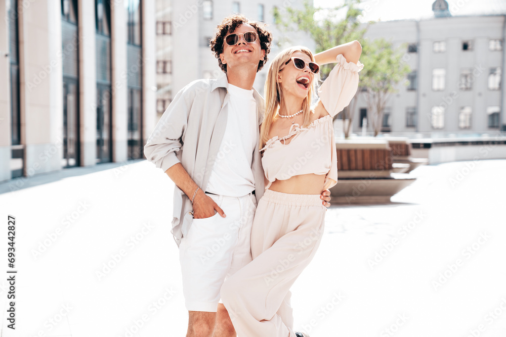 Young smiling beautiful woman and her handsome boyfriend in casual summer clothes. Happy cheerful family. Female having fun. Couple posing in the street background at sunny day. In sunglasses