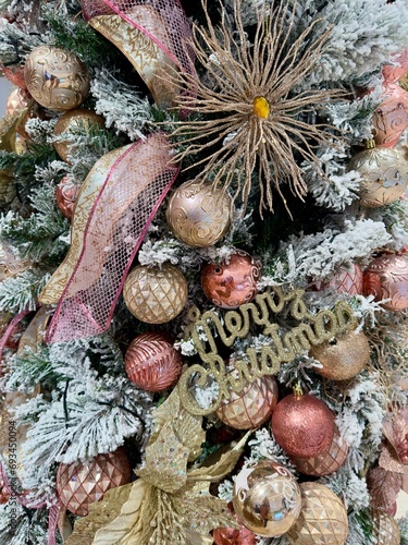 pink rose gold snow christmas tree decorations detail close up with baubles balls and glitter festive ribbon and merry christmas lettering text ornament