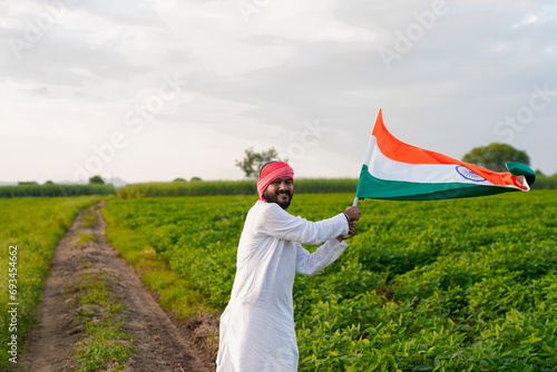 Indian farmer holding indian flag at agriculture field.