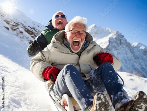 Happy senior couple having fun spending winter vacation in mountains sledding down the slope on a snowy mountain