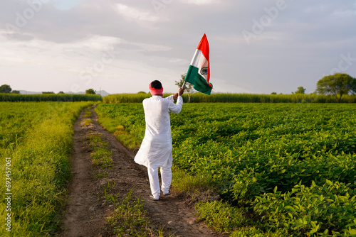 Indian farmer holding indian flag at agriculture field.