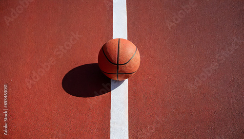Basketball ball is sitting in the red rubber court vertical white line outdoors, top view. copy space.image for sport, exercise concept.High quality image. © ARVD73