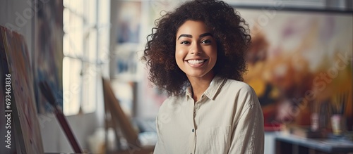 A confident young African American girl relaxingly painting in an art studio, with a natural and contented smile.