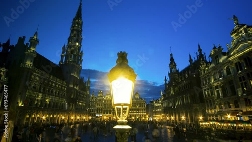 The Grand-Place or Grote Markt at night with tourists is the central square of the city of Brussels. It is surrounded by guild houses, the Hôtel de Ville and the Maison du Roi. UNESCO heritage photo