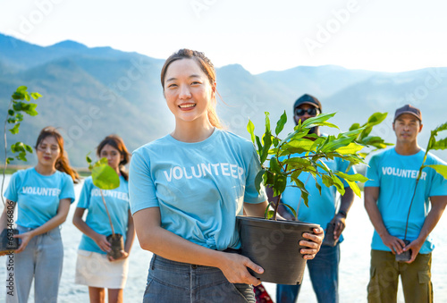 portrait young asian woman in blue volunteer T-shirt holding pot of young sprout plant tree,concept of volunteering,reforestation,conservation of natural resources and the environment