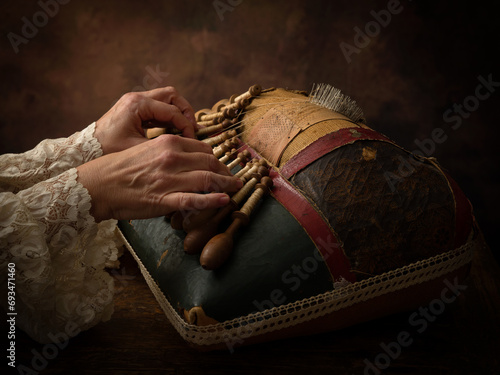 Hands with lace pillow with bobbins