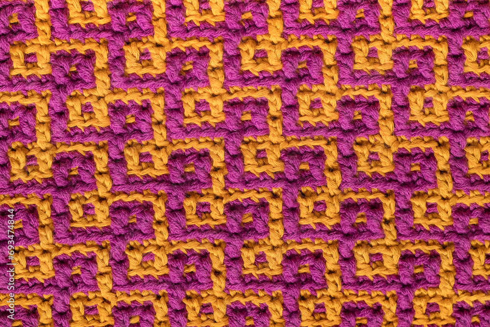 Knitted background. Purple yellow crochet mosaic texture with abstract pattern.
