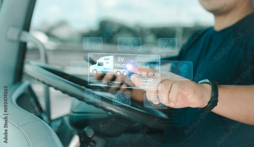 © Nuad Contributor - Man truck driver use fingers virtual screen touches to search for location Electric truck charging station for solar panels and wind turbines. Transportation and driving technology Using clean energy. © Nuad Contributor - Man truck driver use fingers virtual screen touches to search for location Electric truck charging station for solar panels and wind turbines. Transportation and driving technology Using clean energy.