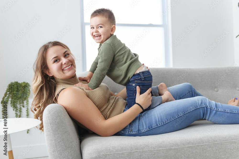 Mature mother with small son on sofa indoors, resting.
