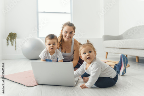 Sport Activities With Baby. Young Mom trying doing Exercising With Her Infant Son At Home