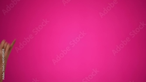 Funny elderly mature woman, 80s, wearing negligee and glasses giving SHAKA hand gesture walking across pink background. Concept of old rock and roll person photo