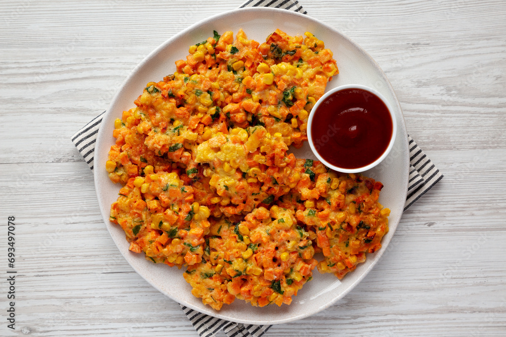 Homemade Carrot Corn Fritters with Ketchup on a Plate, top view. Flat lay, overhead, from above. Homemade Carrot Corn Fritters with Ketchup on a Plate, top view. Flat lay, overhead, from above.