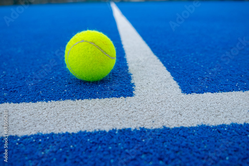 paddle tennis ball at the vertex of the lines of a blue paddle tennis court © Vic
