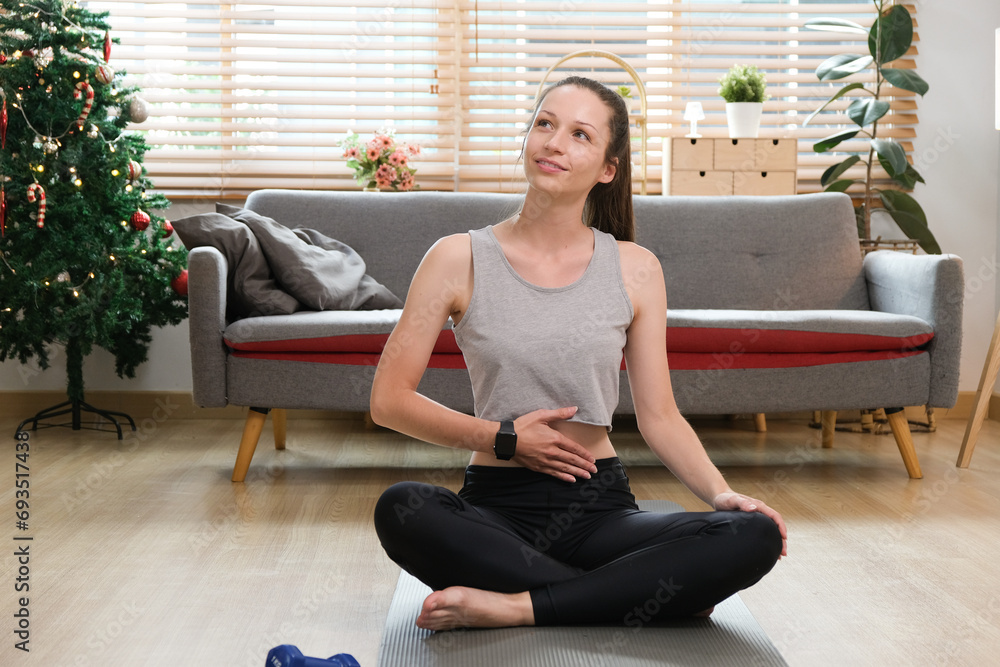 Happy woman in sportswear having a yoga workout at home. Beautiful fit young woman in sports leggings and crop top standing on an exercise mat in the living room and doing a forward lunge exercise Happy woman in sportswear having a yoga workout at home. Beautiful fit young woman in sports leggings and crop top standing on an exercise mat in the living room and doing a forward lunge exercise