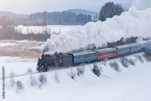 Retro christmas steam train moves along the frozen lake.