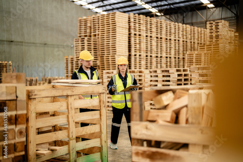 workers man and woman engineering walking and inspecting timbers wood in warehouse. Concept of smart industry worker operating. Wood factories produce wood palate. © ultramansk