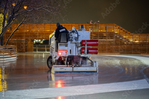 Ice preparation at rink. Ice rink resurfacer vehicle resurface machine outdoor between session. Maintenance. photo