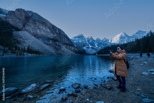 Female tourist carries a backpack, travels, walks, the beauty of the reflection in the water of moraine Lake, Canadian Rocky Mountains