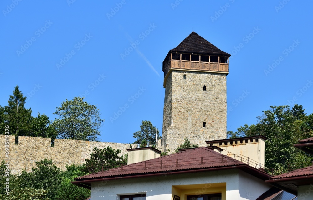 The contrast between the modern roof of the building and the historic tower
